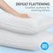 A pair of white, fluffy sleeping pillows with deep grooves, being touched by a hand to demonstrate their softness and texture. The image encourages touch and emphasizes comfort.