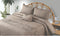 A double bed covered with a beige bed cover set, featuring a frill breakfast pillow and two pillow covers, placed in a room with decor.