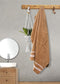 Brown towel with white trim hanging on a wooden towel rack in a bathroom.