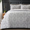 Gray floral patterned comforter set on a bed with a dark headboard.
