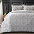 Gray floral patterned comforter set on a bed with a dark headboard.