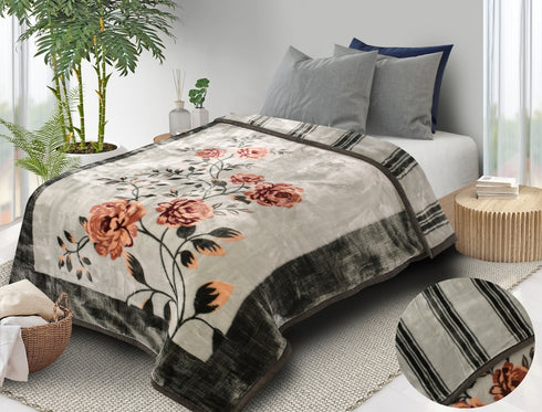 A two-ply minky blanket with a floral print on one side and solid color on the other, displayed on a bed in a room with decorative plants and a partial view of the reverse side shown.