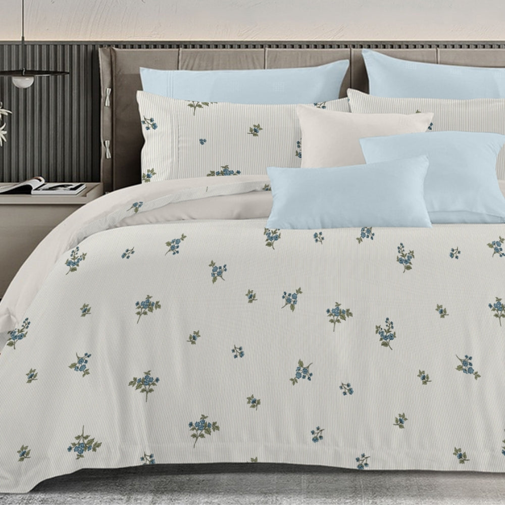 Floral patterned bedding set on a bed with light blue and white pillows.