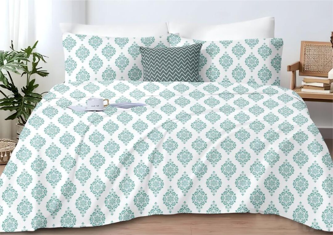 Teal and white patterned comforter set on a bed with pillows and a plant in the background.