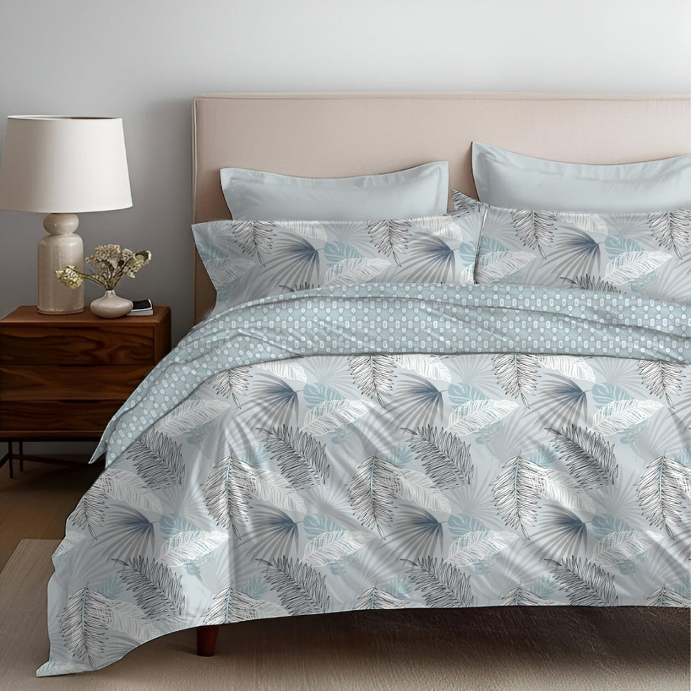 A bed with a comforter set featuring a leaf pattern in multiple colors, with a duvet cover, bedsheet, and pillowcases displayed.