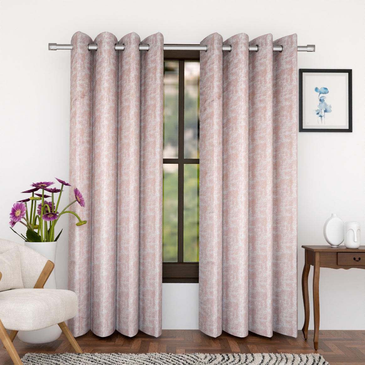 A pair of pink curtains with embroidery details hanging on a window in a room with a chair, flower vase, and a framed picture on the side.