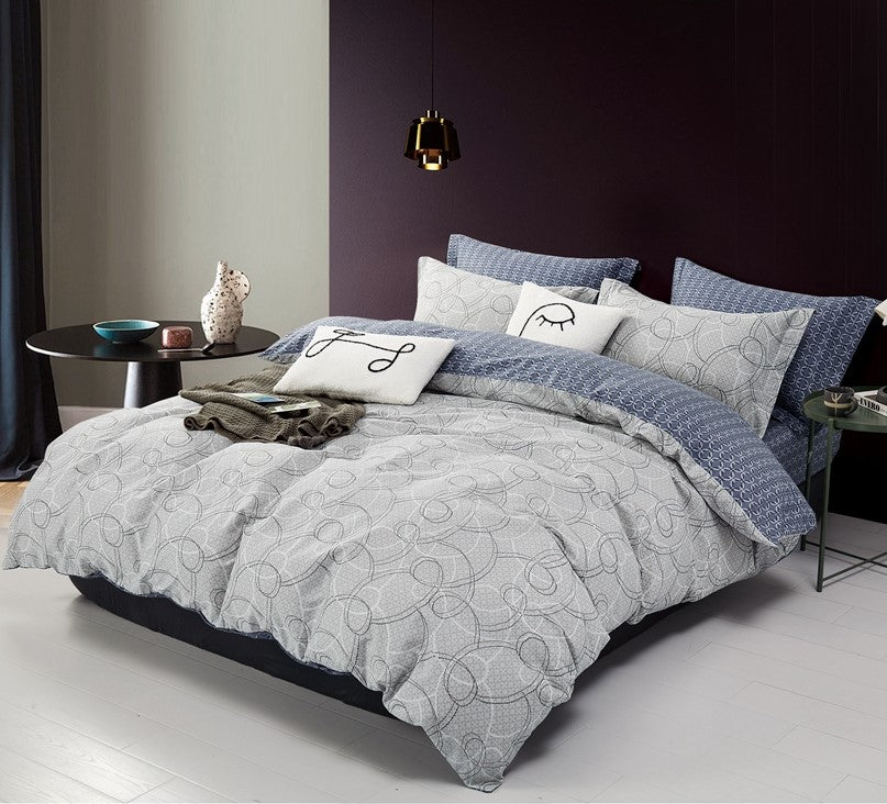 A king-size bed with a gray and white geometric patterned bed sheet set, including two pillow covers, in a room with dark purple walls.