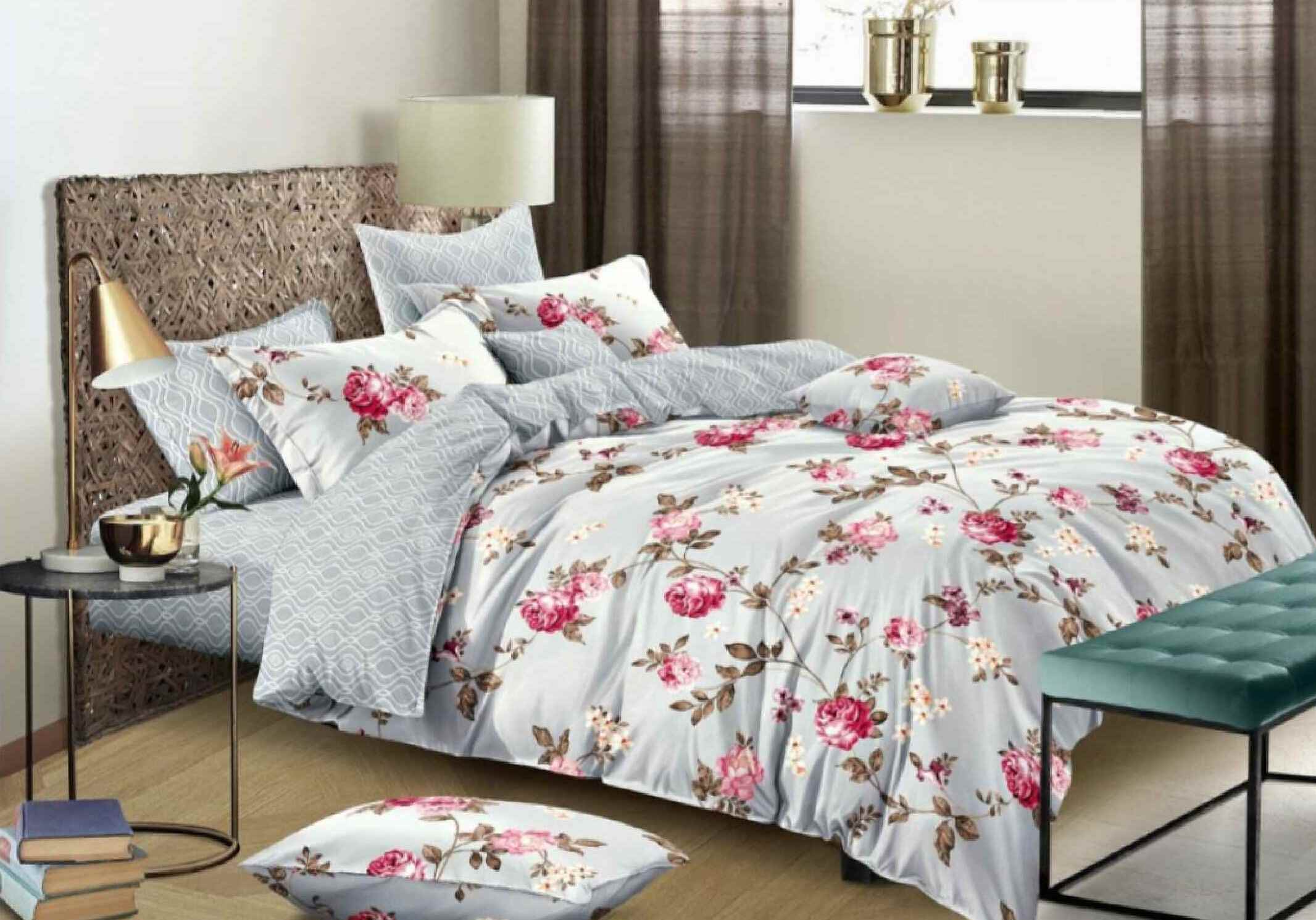 A floral printed top sheet on a bed, with pillows arranged on the bed, in a bedroom setting.